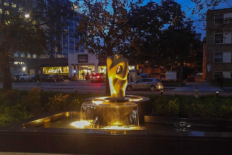 Water feature designed around a historic artist’s sculpture in Toronto, lit at night
