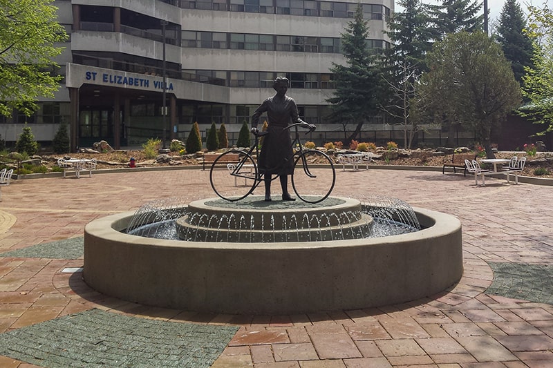 Bronze sculpture standing in a circular fountain basin in Toronto