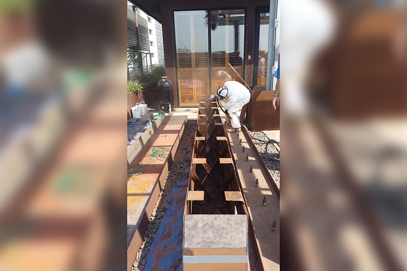 Corten steel water channel being resealed during a fountain restoration in Toronto