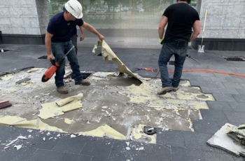 This image shows a construction worker removing failed waterproofing. This waterproofing is supposed to be adhered to the concrete and not removable by pulling. It was identified the waterproofing was potentially installed on non-cured concrete.